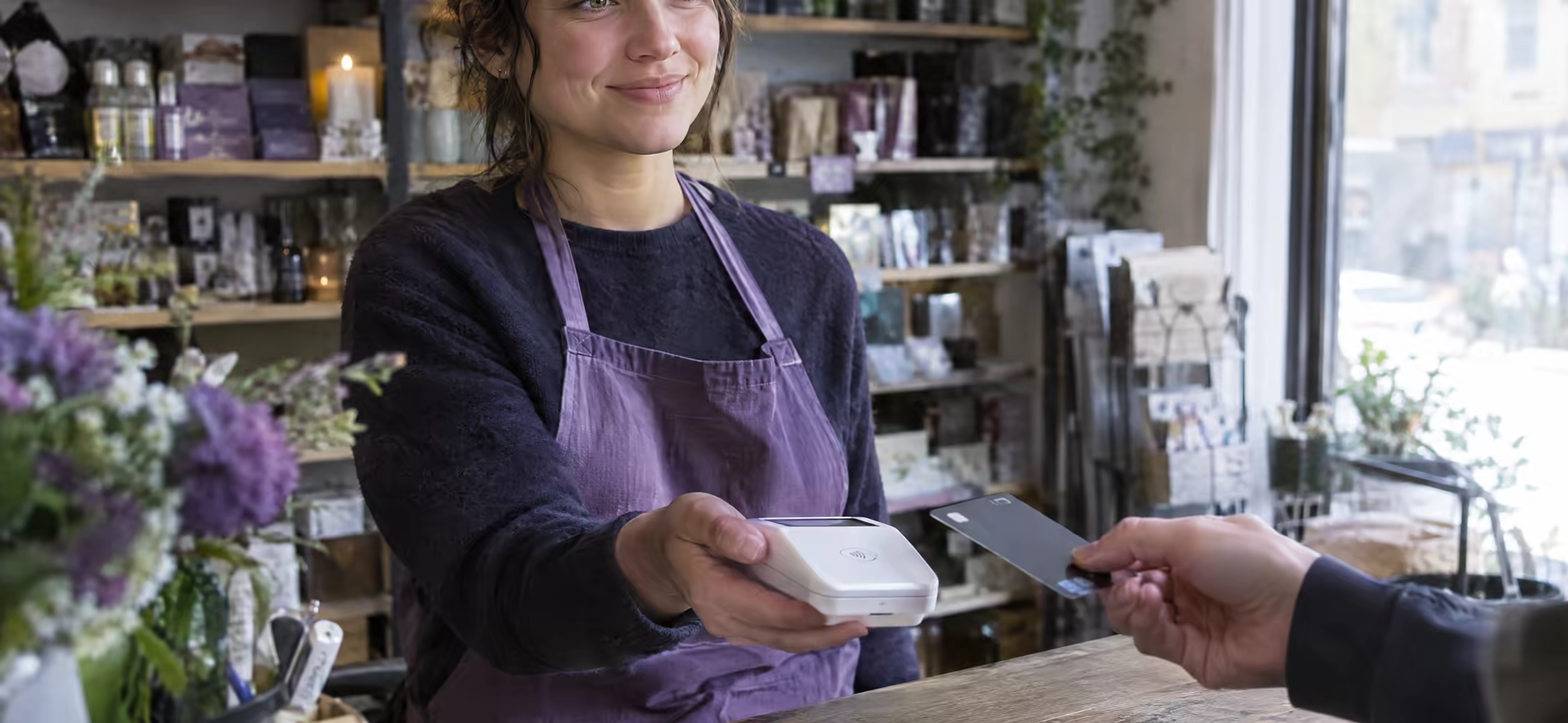 A shopkeeper holding out a card reader across the counter